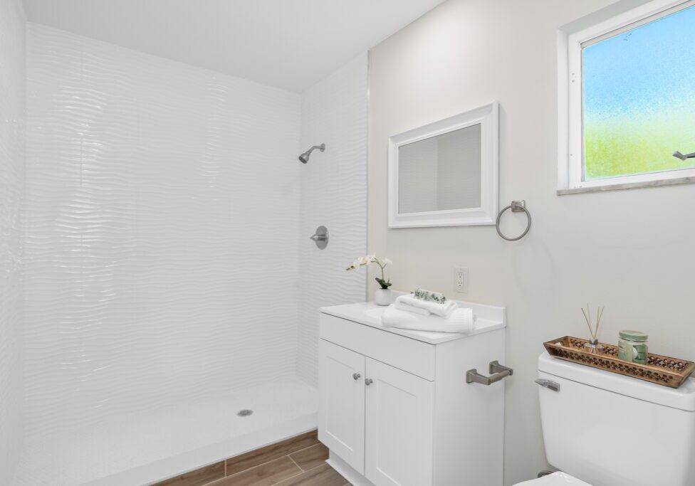 Bright and clean white bathroom with modern fixtures and a walk-in shower.