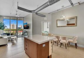 Modern open-concept kitchen and dining area with city view balcony.