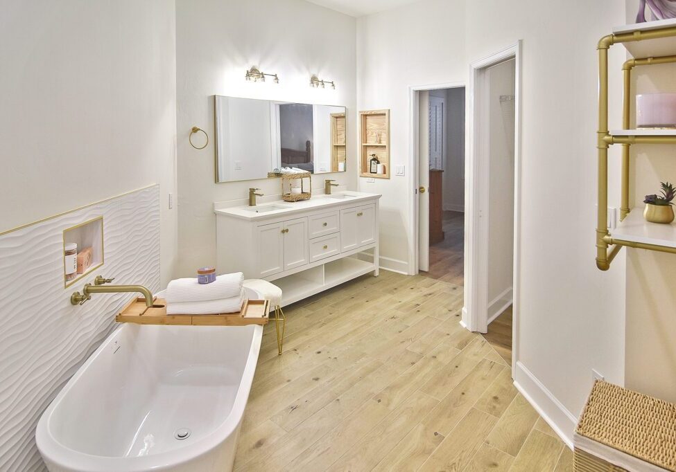 Bright, modern bathroom with white fixtures and light wooden flooring.