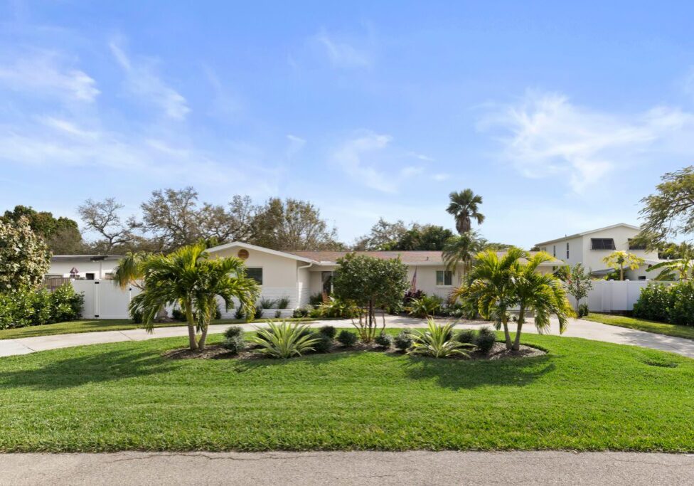 A single-story house with a well-maintained front yard and palm trees.